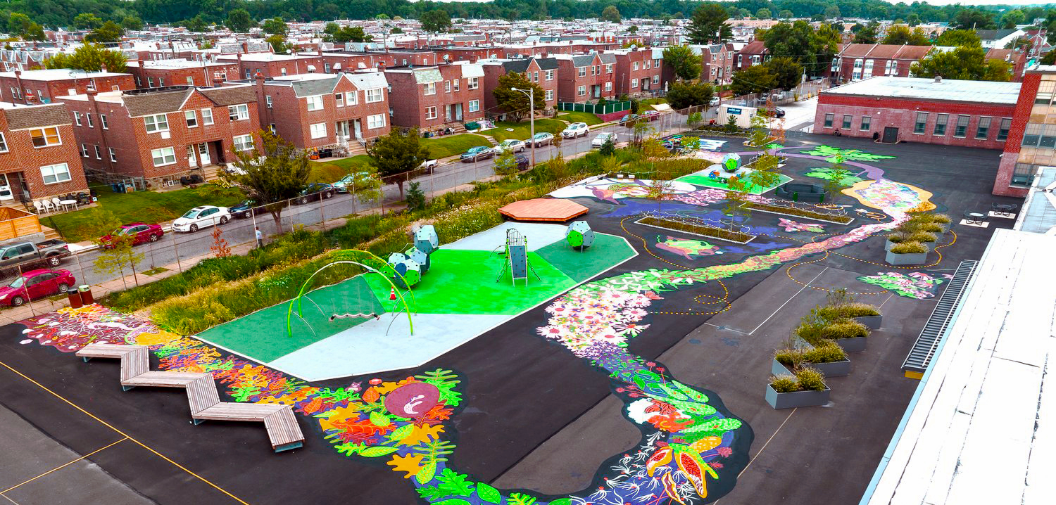 Aerial View of Farrell Elementary School’s Vibrant Schoolyard A wide aerial view of Farrell Elementary School’s colorful schoolyard featuring a large painted mural resembling a winding stream surrounded by floral and nature-inspired designs. The playground includes modern play structures, seating areas, garden planters, and a basketball court, all set against a backdrop of residential homes.